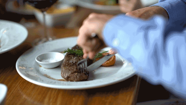 Man cutting steak dinner at table
