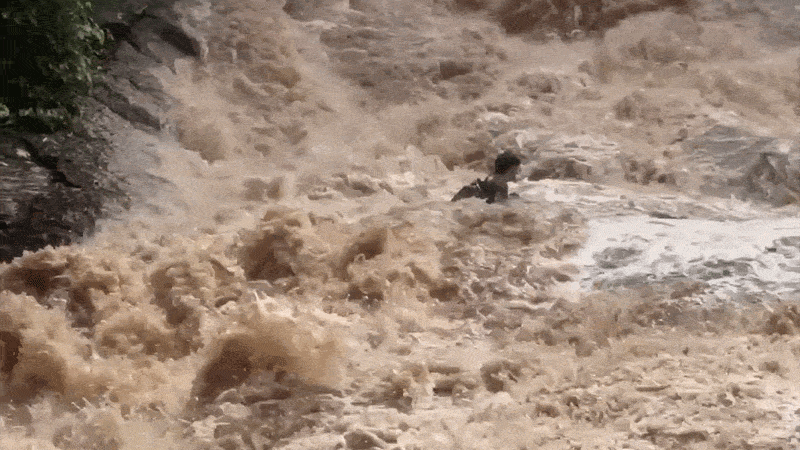 A boy is seen stranded in powerful currents at a waterfall in Thailand.
